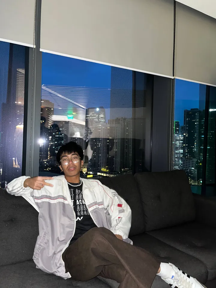 Salvador Vincent Javier sitting on a couch in front of the Manila skyline at night
